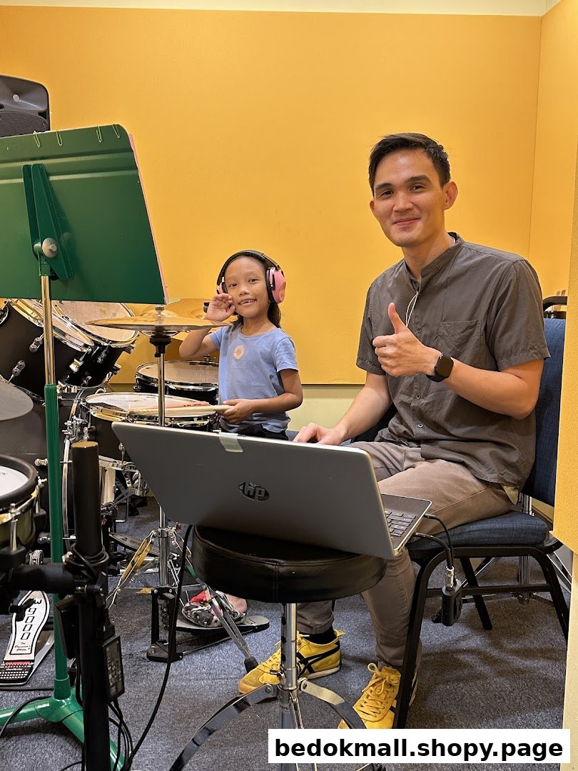 Adult and child in a music room with drums and a laptop.