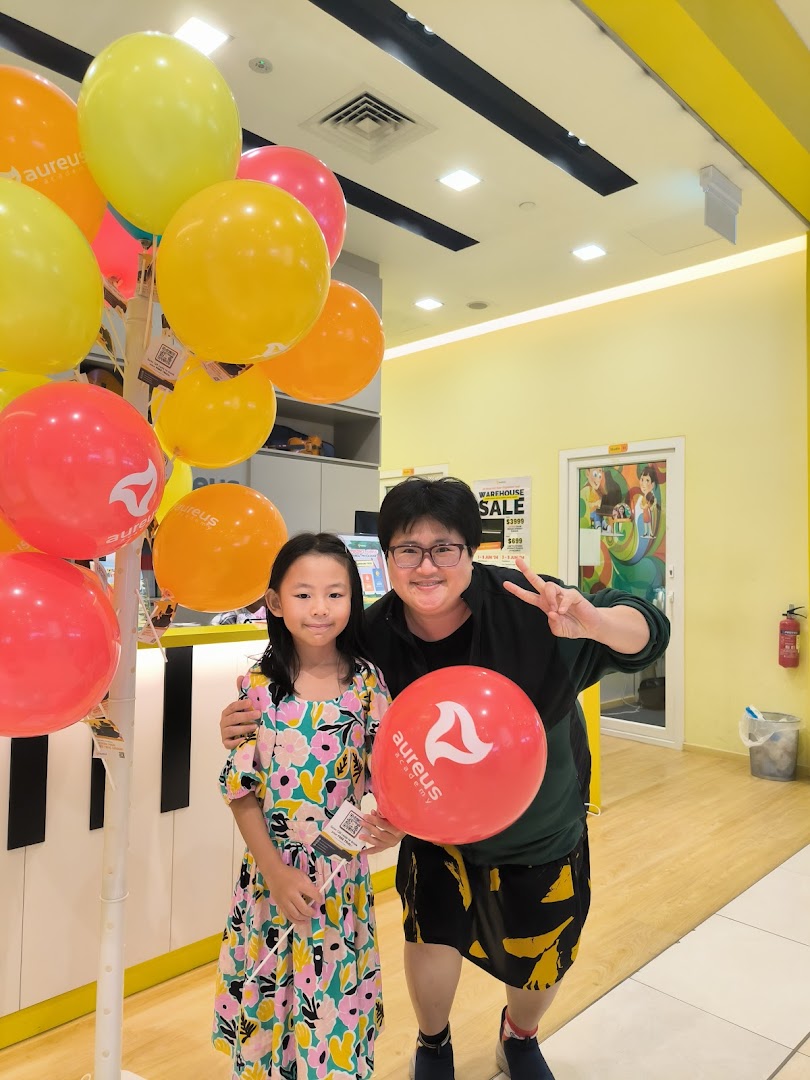 Two people pose with balloons inside Aureus Academy.