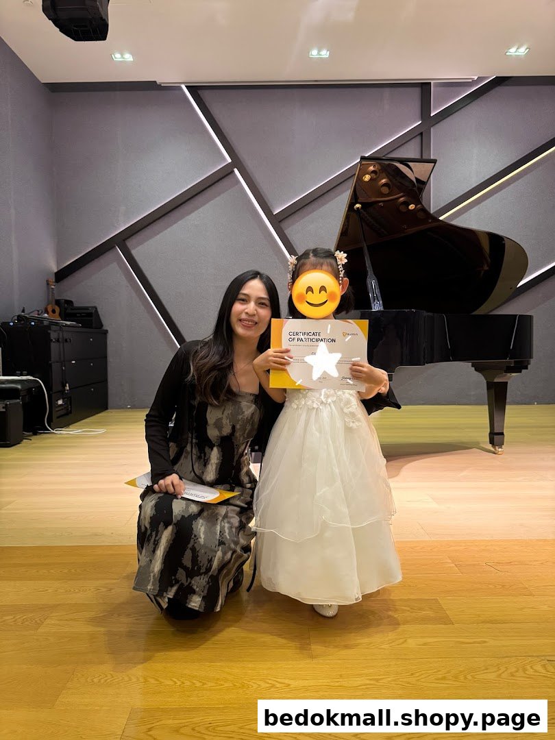 Adult and child with certificate in a music room with a grand piano.