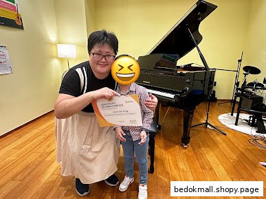 Adult and child holding a certificate in a music room with a grand piano.