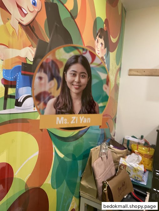 Interior wall with a large graphic, a photo of Ms. Zi Yan, and bags.