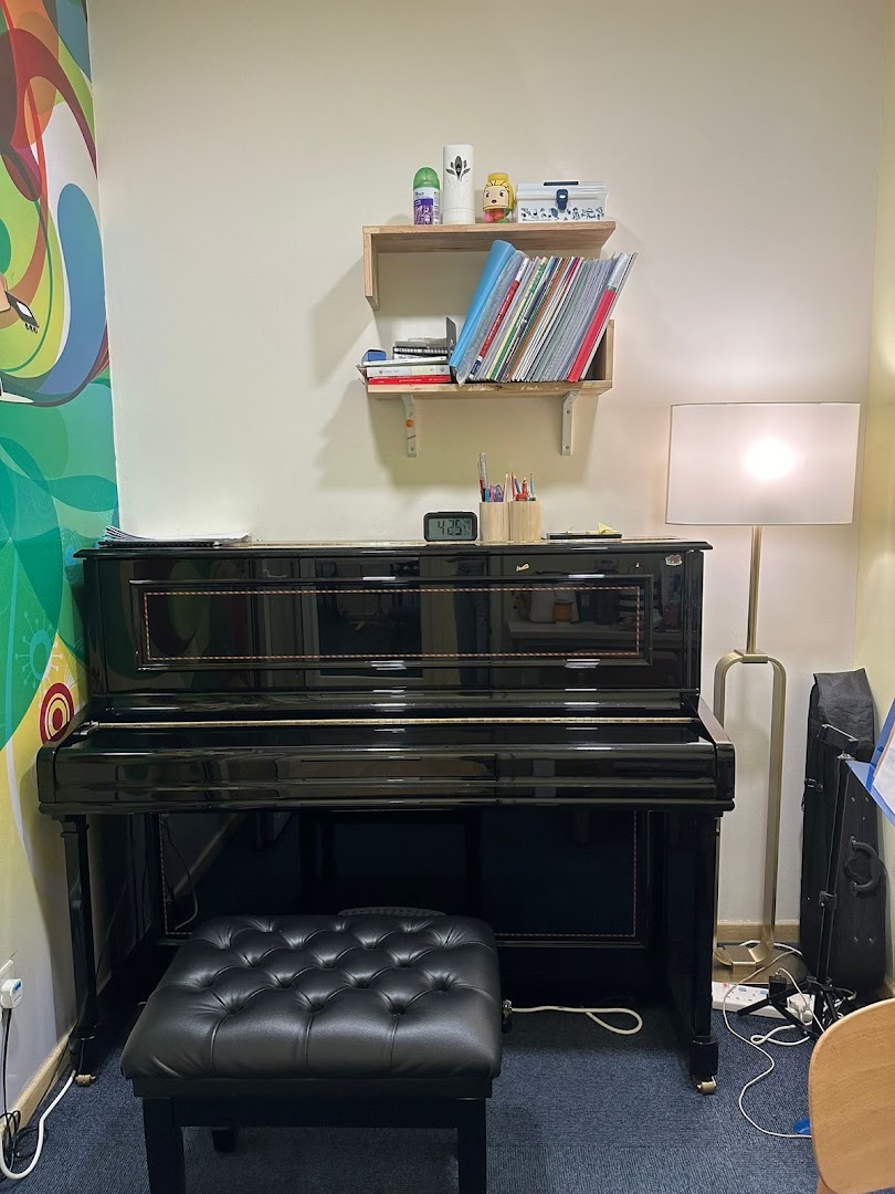 An interior shot of a music room with a black piano and shelves.