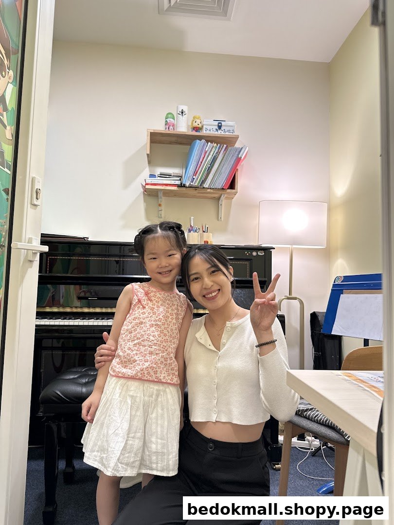 An adult and child pose in a music academy room with a piano.