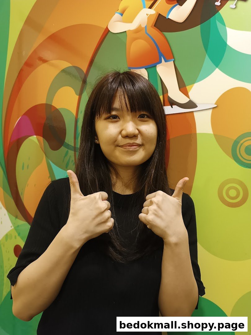Smiling person gives thumbs up against a colorful wall.