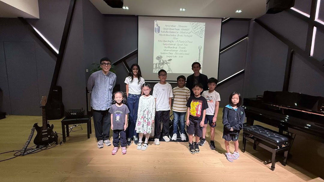 Group of people with musical instruments and a projector screen in a studio.