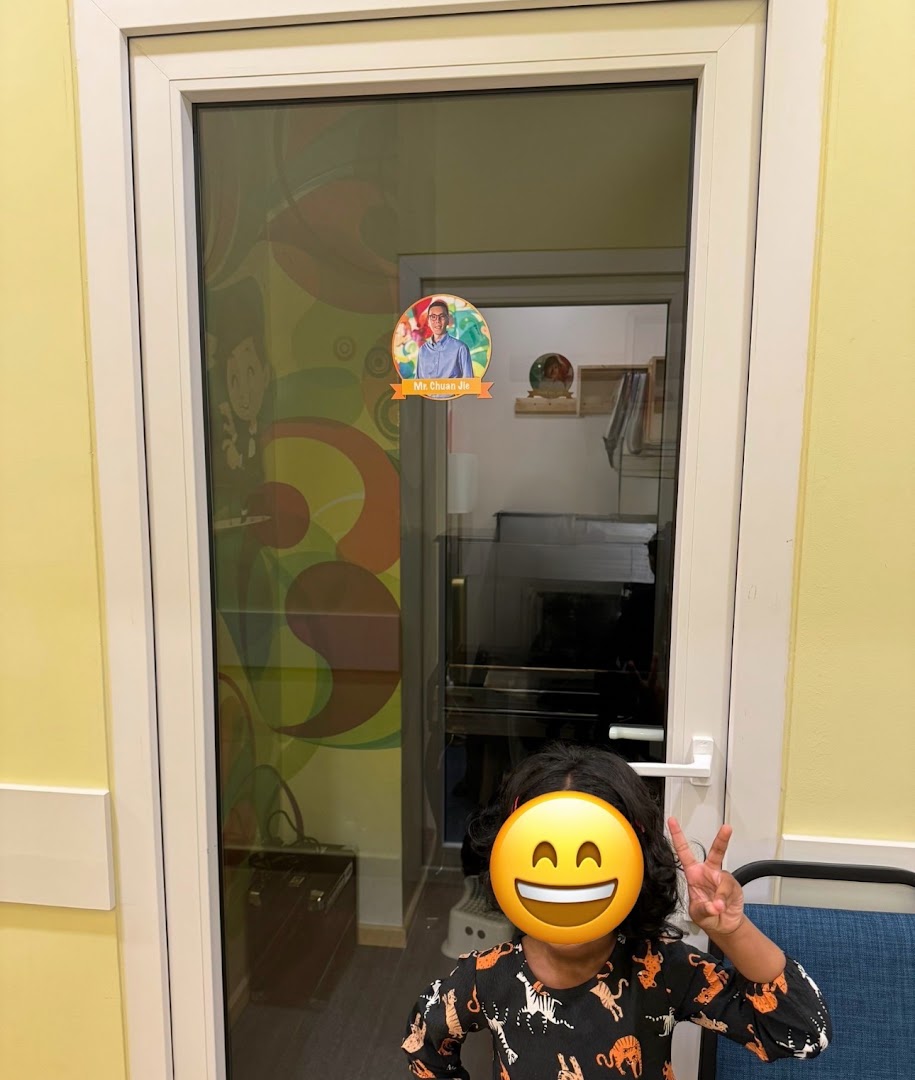 Child stands in front of a glass door leading to a colorful interior room.