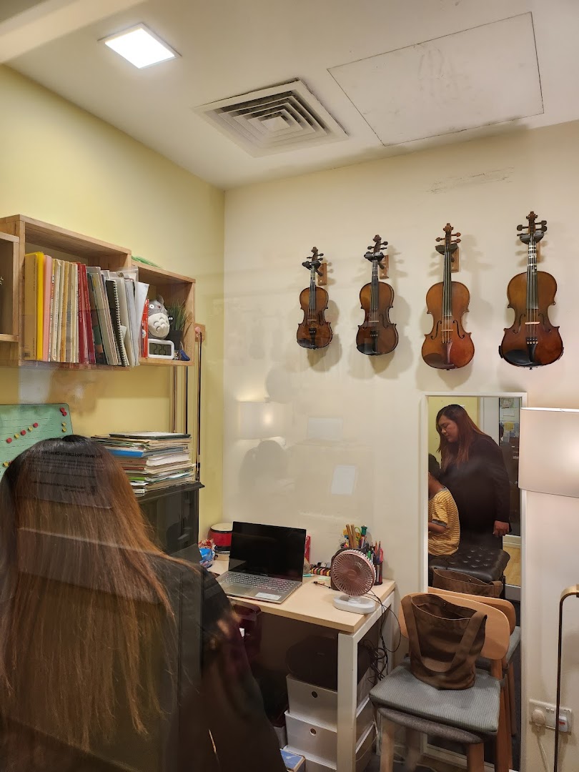 Interior shot of a music academy with violins on display and a desk.