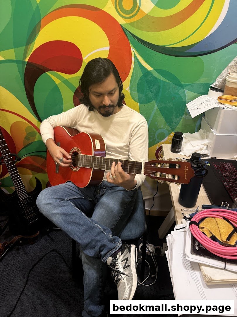 A person plays a red acoustic guitar in a colorful room.