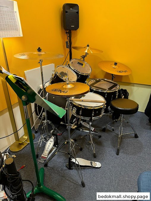A drum set in a music room with yellow walls and a music stand.