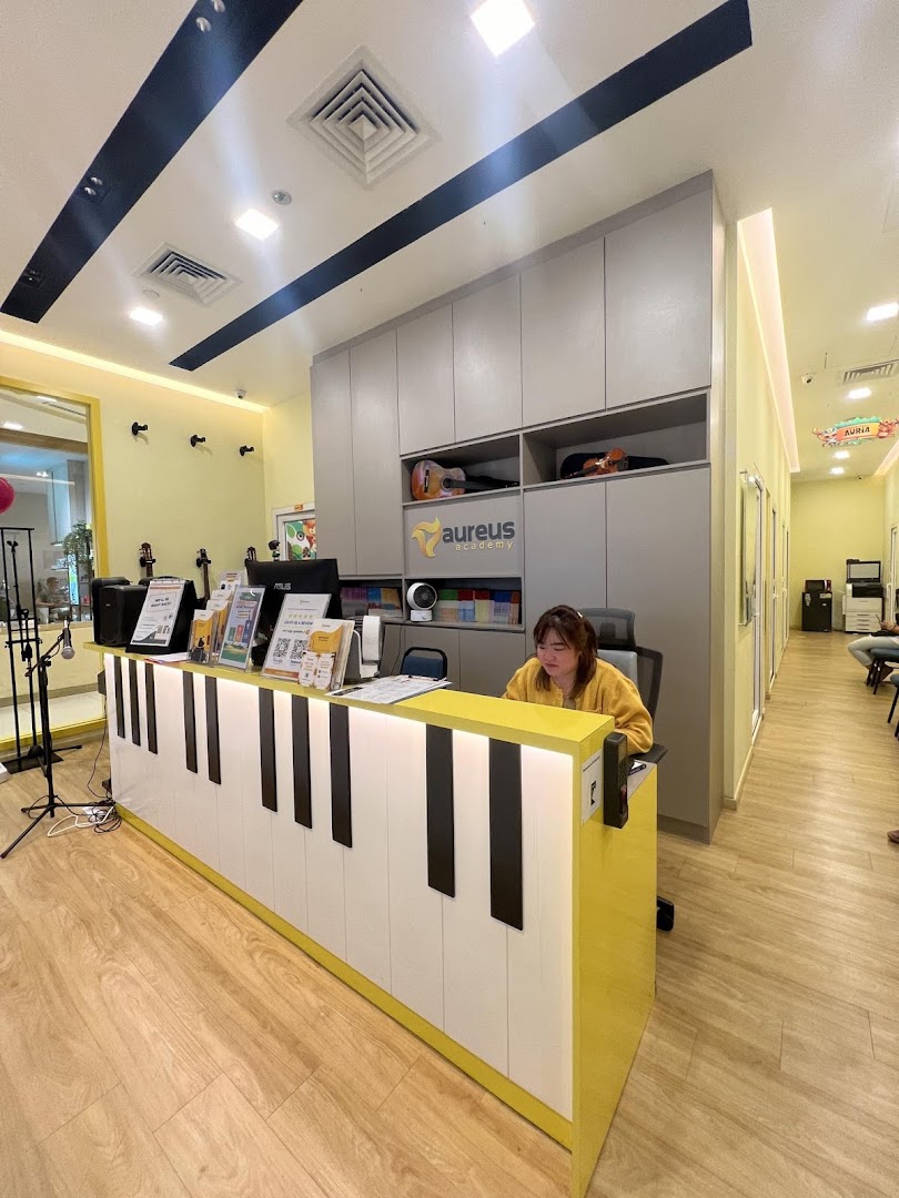 Interior of Aureus Academy with a piano-themed reception desk and staff.