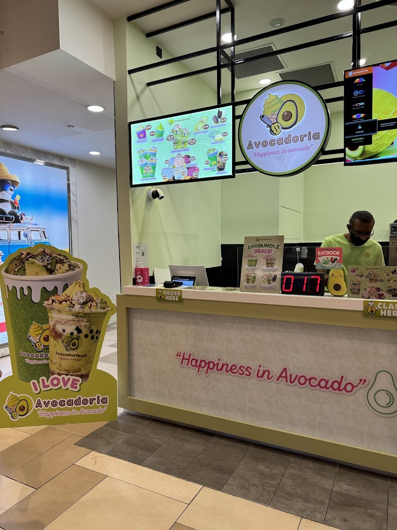 Shop counter with staff, digital menus, and branding for Avocadoria.