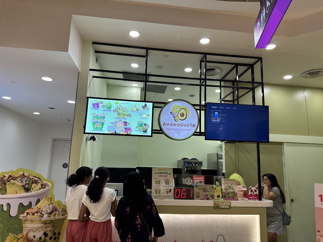 Avocadoria shop interior showing customers at the counter and a digital menu.