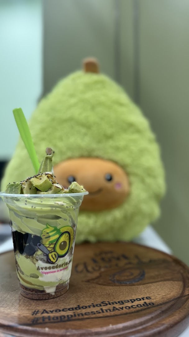 Avocado dessert cup with a green plush avocado toy in the background.