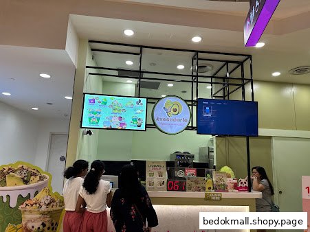 Customers at a shop counter with menu screens and branding for Avocadoria.
