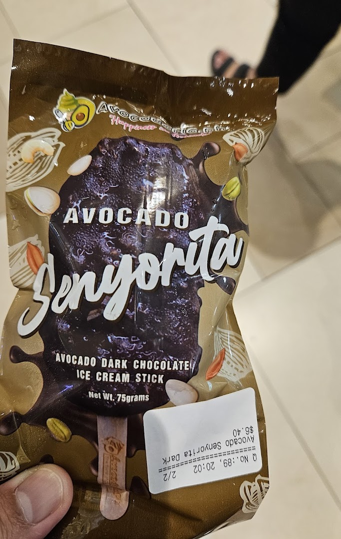 A hand holds a packaged dark chocolate avocado ice cream stick with a price tag.