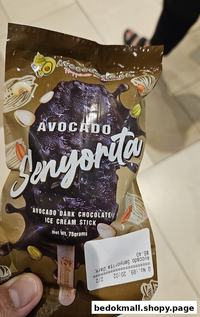 A hand holds a packaged dark chocolate avocado ice cream stick with a price tag.