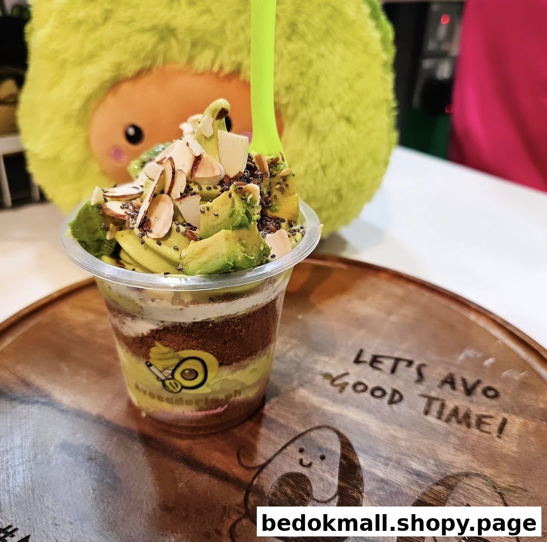 A layered avocado dessert in a cup with toppings on a wooden tray.