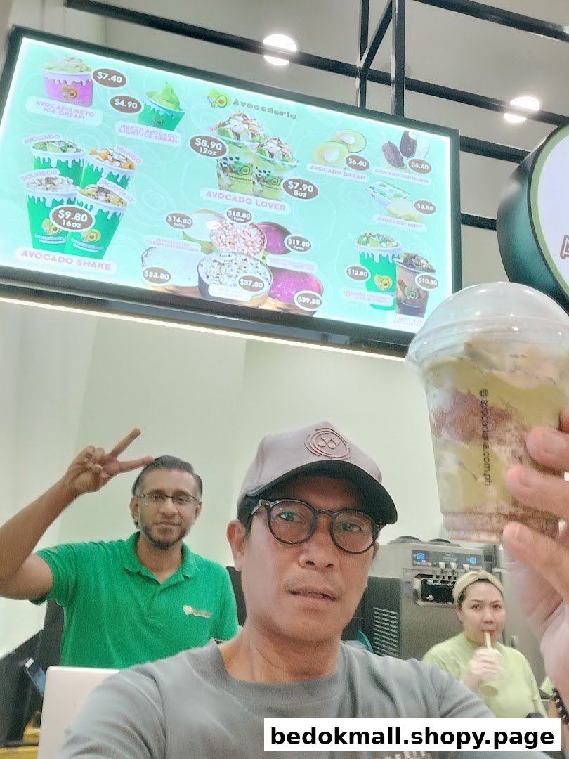 A person holds a drink in front of a large digital menu board.