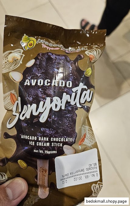 A hand holds a packaged avocado dark chocolate ice cream stick.