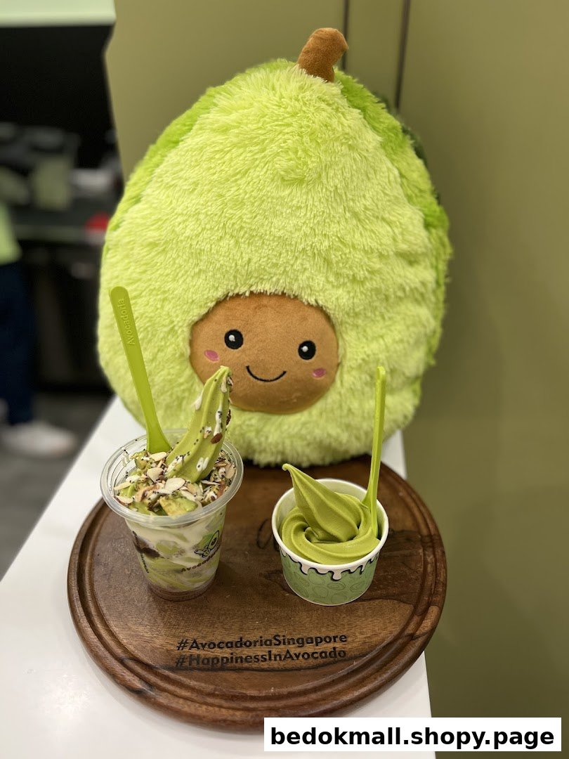 Two avocado desserts and a large avocado plush toy on a wooden tray.