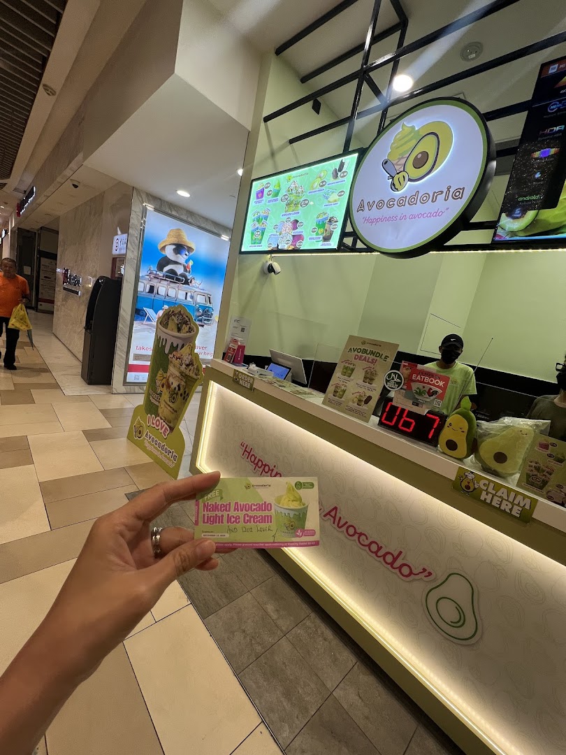 Interior shot of Avocadoria counter with signage and a person holding a card.