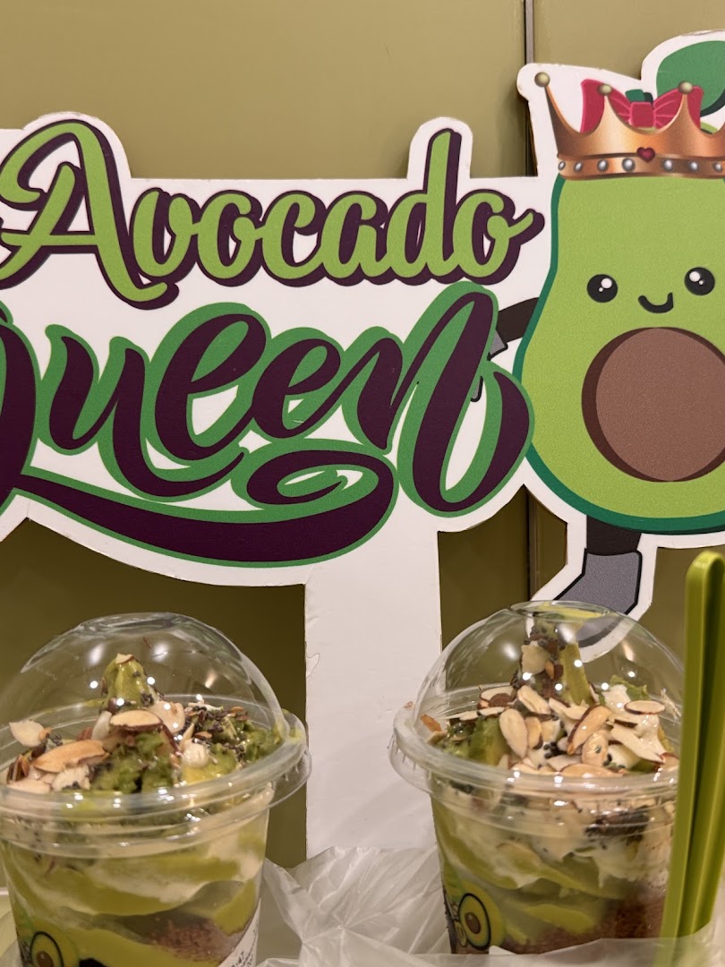 Two avocado desserts in cups with a decorative 'Avocado Queen' sign.