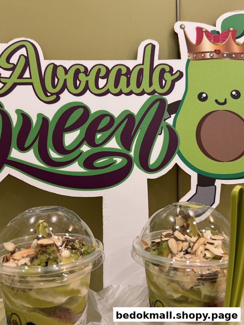 Two avocado desserts in cups with a decorative 'Avocado Queen' sign.