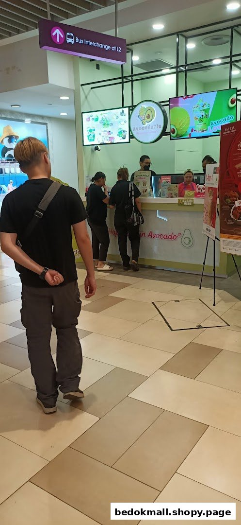 People are at a shop counter with digital displays showing avocado products.