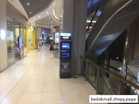 AXS machine in a mall corridor next to an escalator.