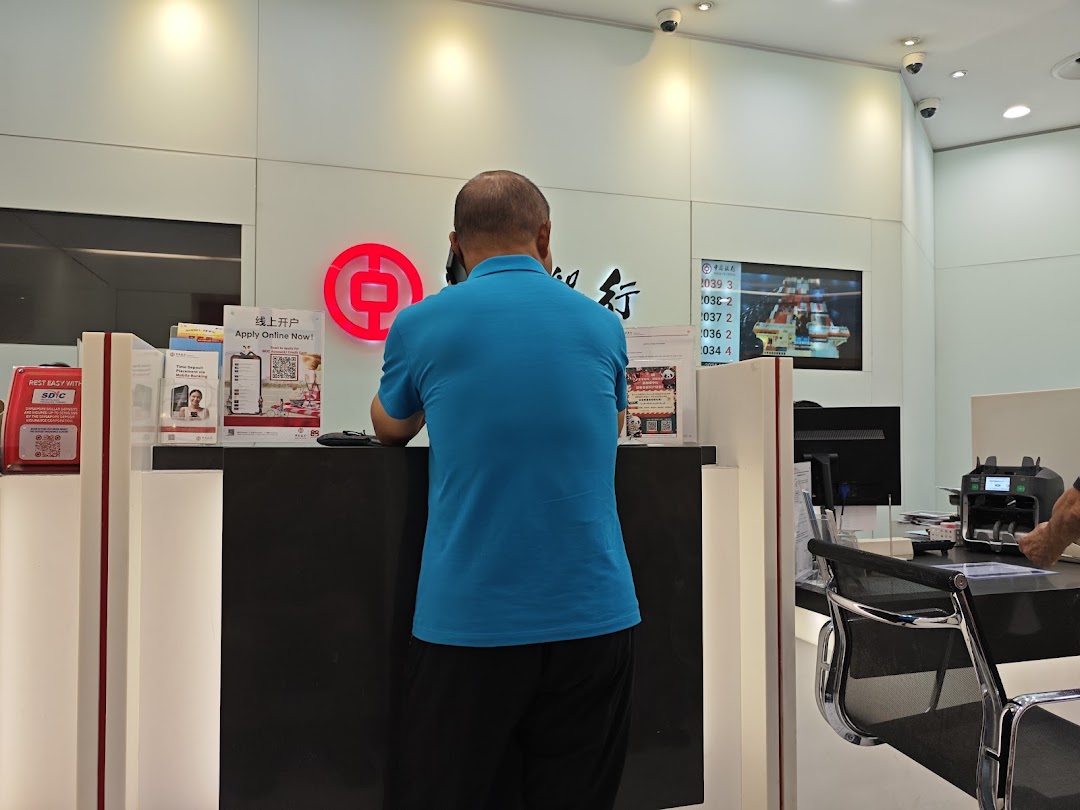 A person stands at a counter inside a Bank of China branch.