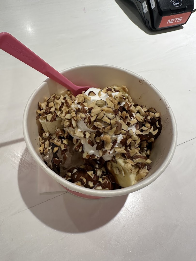 Ice cream sundae with nuts, banana, and whipped cream in a cup.