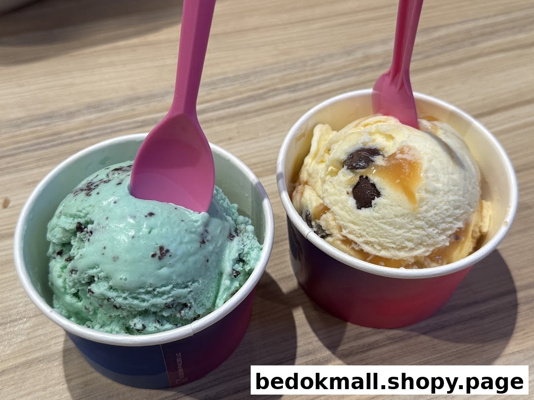 Two cups of ice cream with pink spoons on a wooden surface.