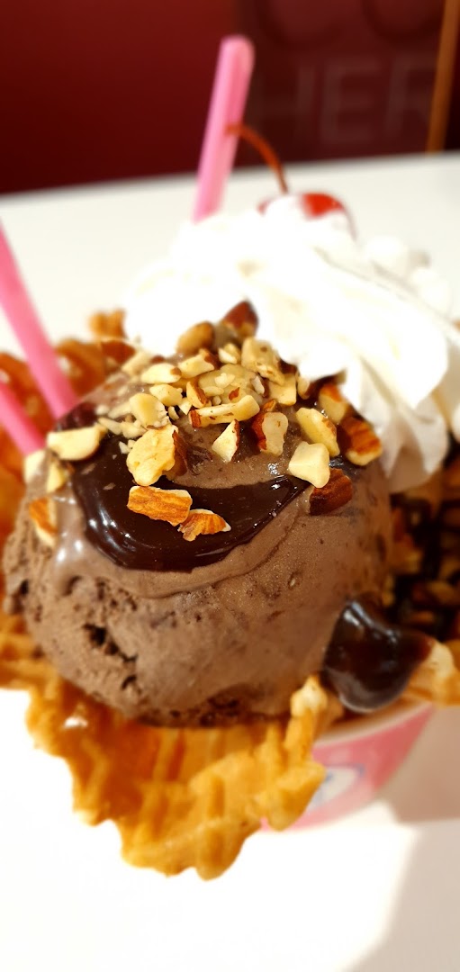 Close-up of chocolate ice cream sundae with nuts, whipped cream, and cherry.