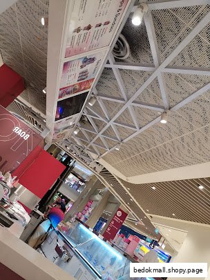 Interior view of an ice cream shop with counter, displays, and overhead menu boards.