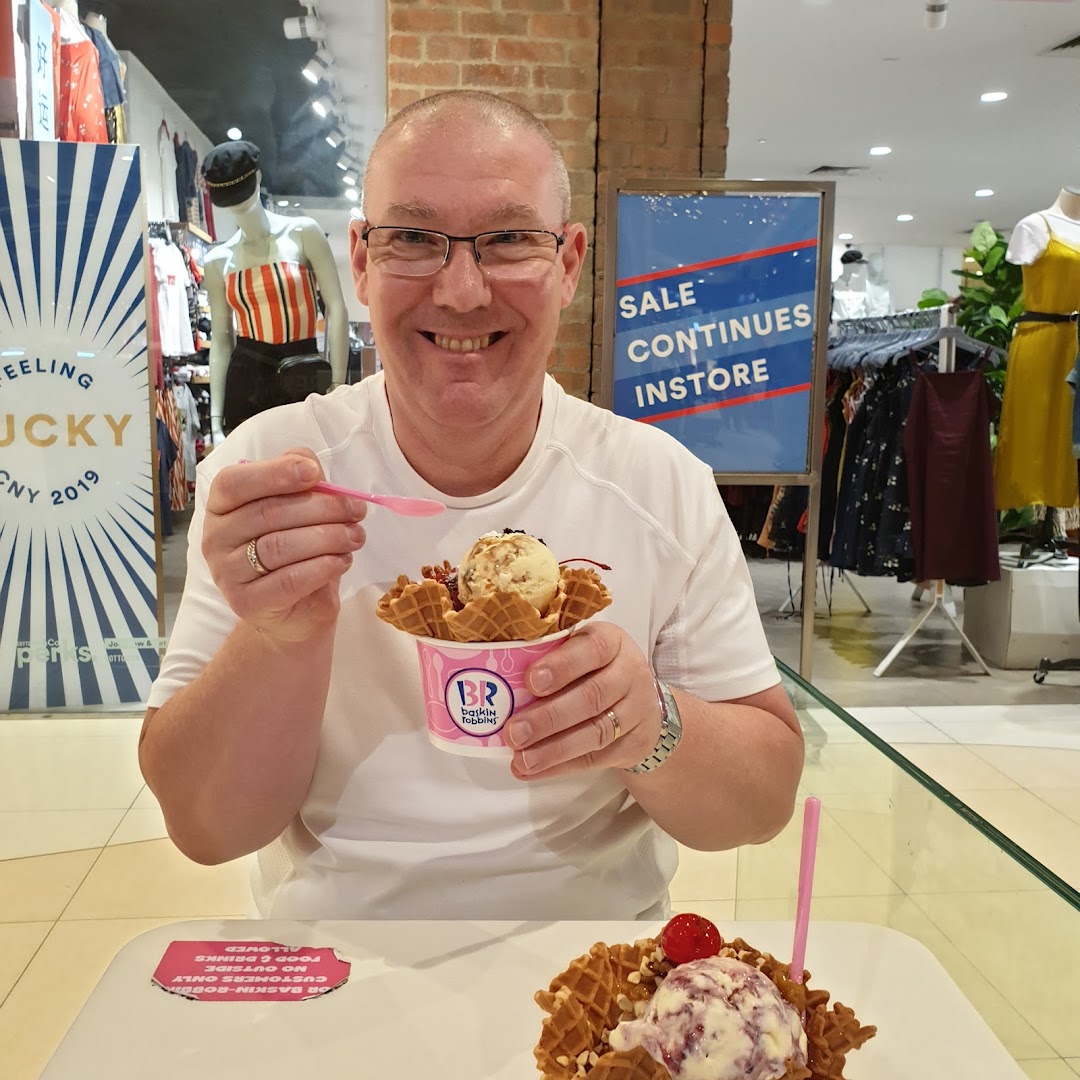Man enjoying Baskin-Robbins ice cream inside a retail environment.