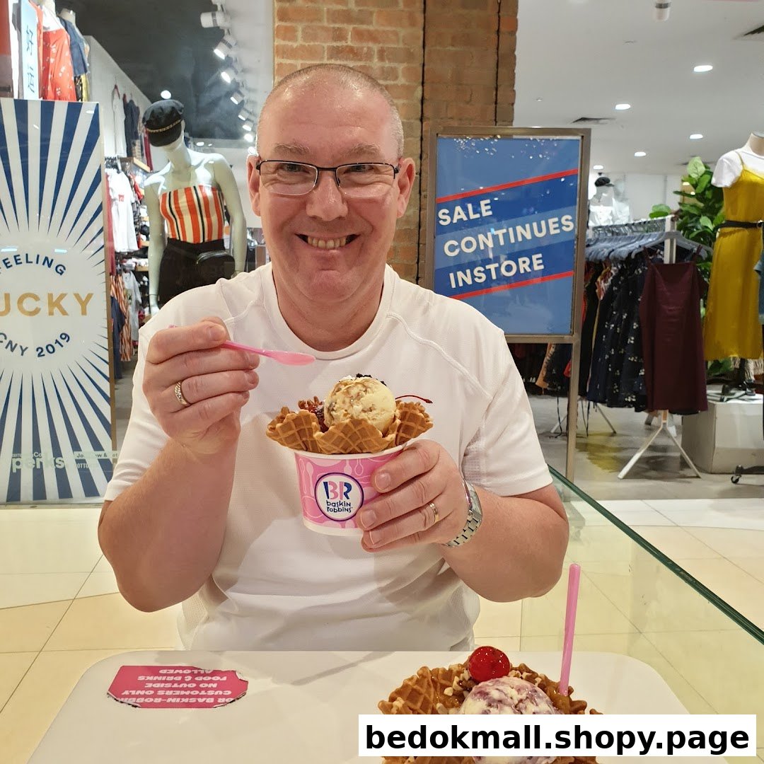 Man enjoying Baskin-Robbins ice cream inside a retail environment.