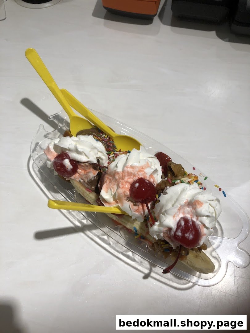 A banana split dessert with whipped cream, cherries, and sprinkles in a clear dish.