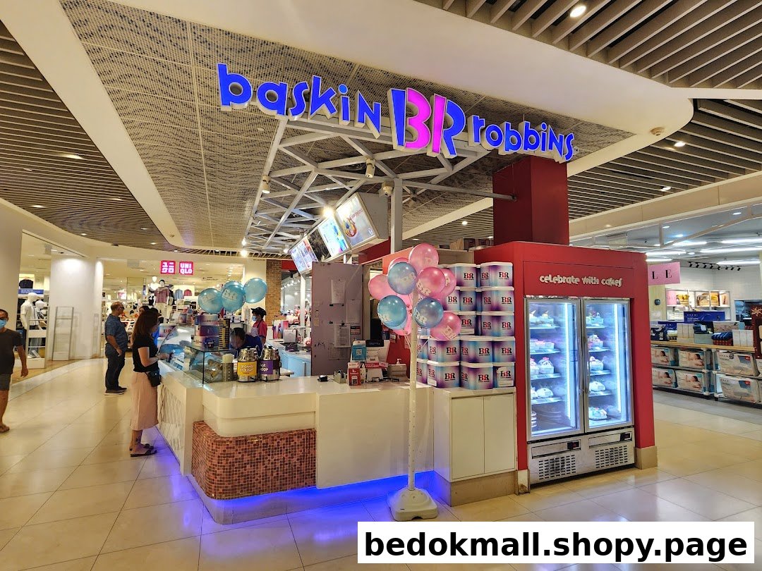 Interior view of a Baskin-Robbins kiosk with counter, cakes, and customers.