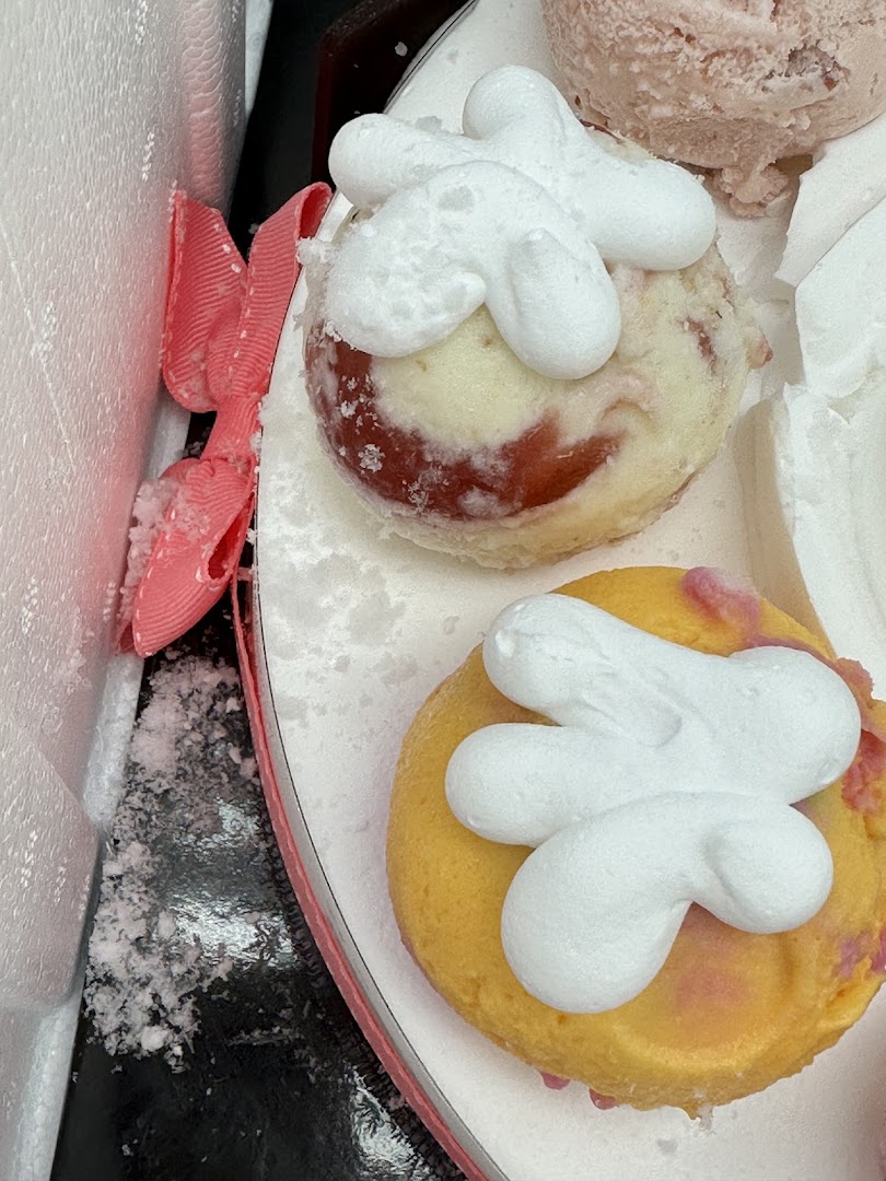 Two round desserts with white frosting and a pink ribbon.