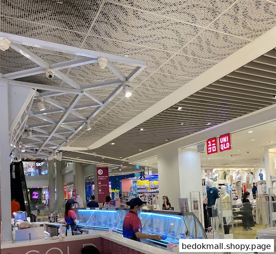 Interior mall view showing a retail counter with staff and a UNIQLO store.