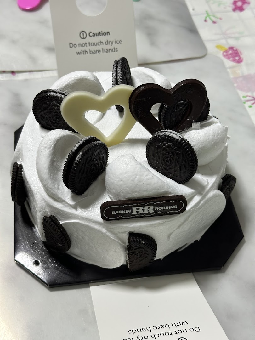 A Baskin-Robbins ice cream cake with white frosting, Oreos, and heart decorations.