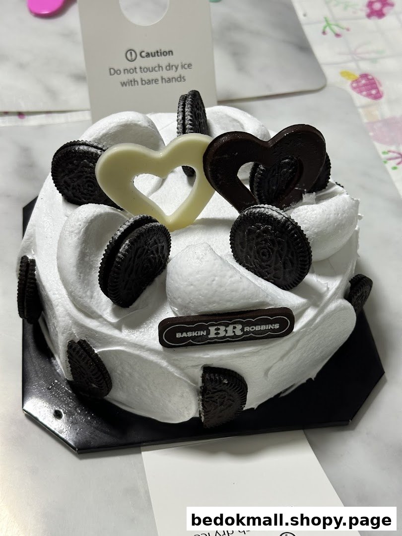 A Baskin-Robbins ice cream cake with white frosting, Oreos, and heart decorations.