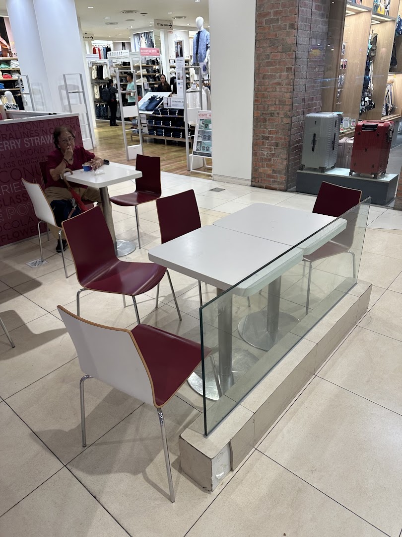 Interior view of a mall seating area with tables, chairs, and a person.