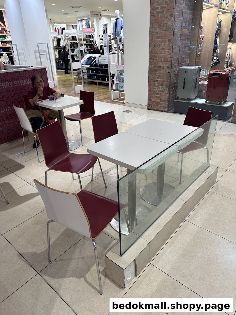 Interior view of a mall seating area with tables, chairs, and a person.