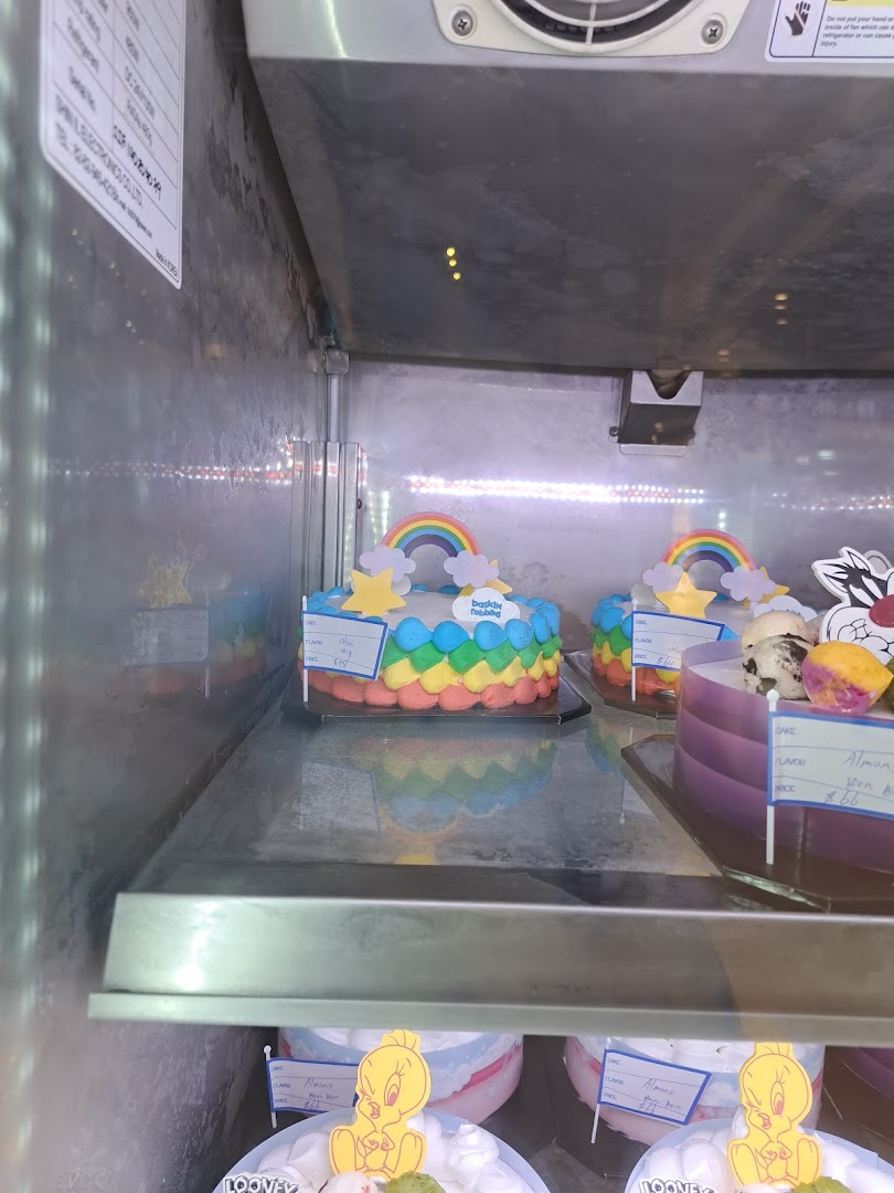 Colorful ice cream cakes with rainbow and character designs displayed in a freezer.