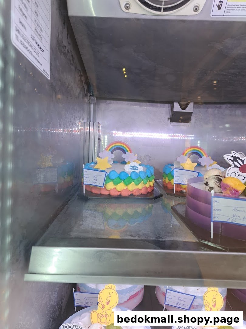 Colorful ice cream cakes with rainbow and character designs displayed in a freezer.