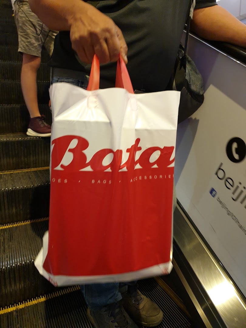 Person holding a Bata shopping bag while riding an escalator.
