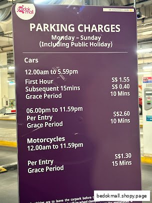A sign displaying parking charges for cars and motorcycles at Bedok Mall.