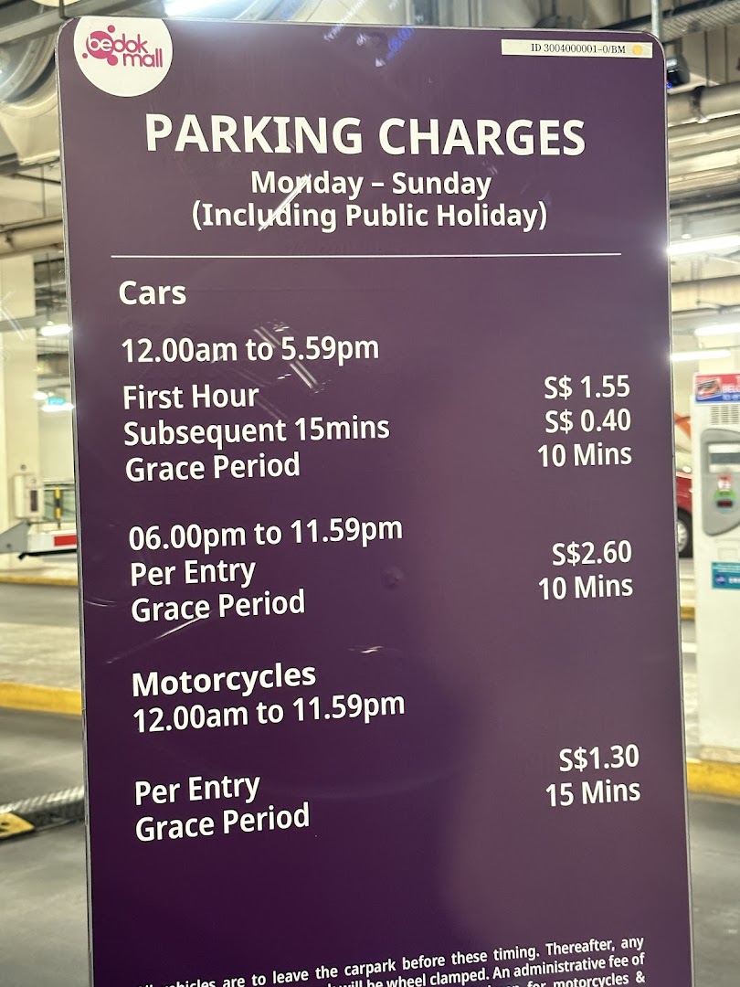 A sign displaying parking charges for cars and motorcycles at Bedok Mall.