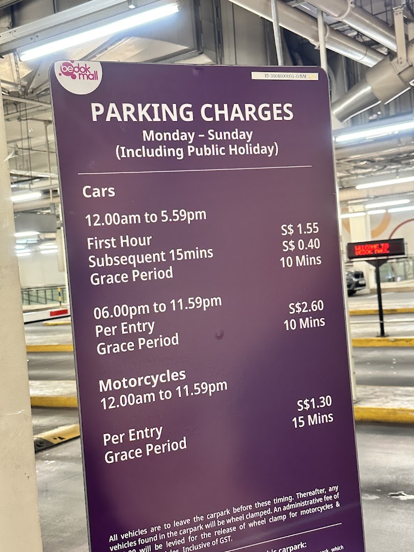 A sign displaying parking charges for cars and motorcycles at Bedok Mall.